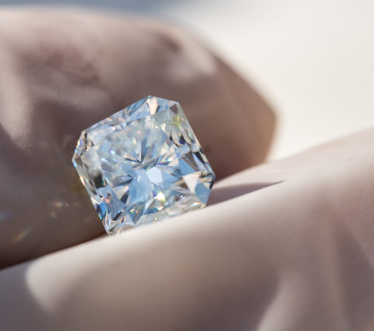 un diamant rectangulaire tenu avec des gants
